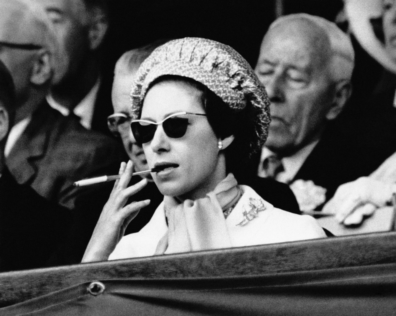У 1965 році принцеса Маргарет курила сигарету на трибуні у протисонцевих окулярах та великому капелюсі