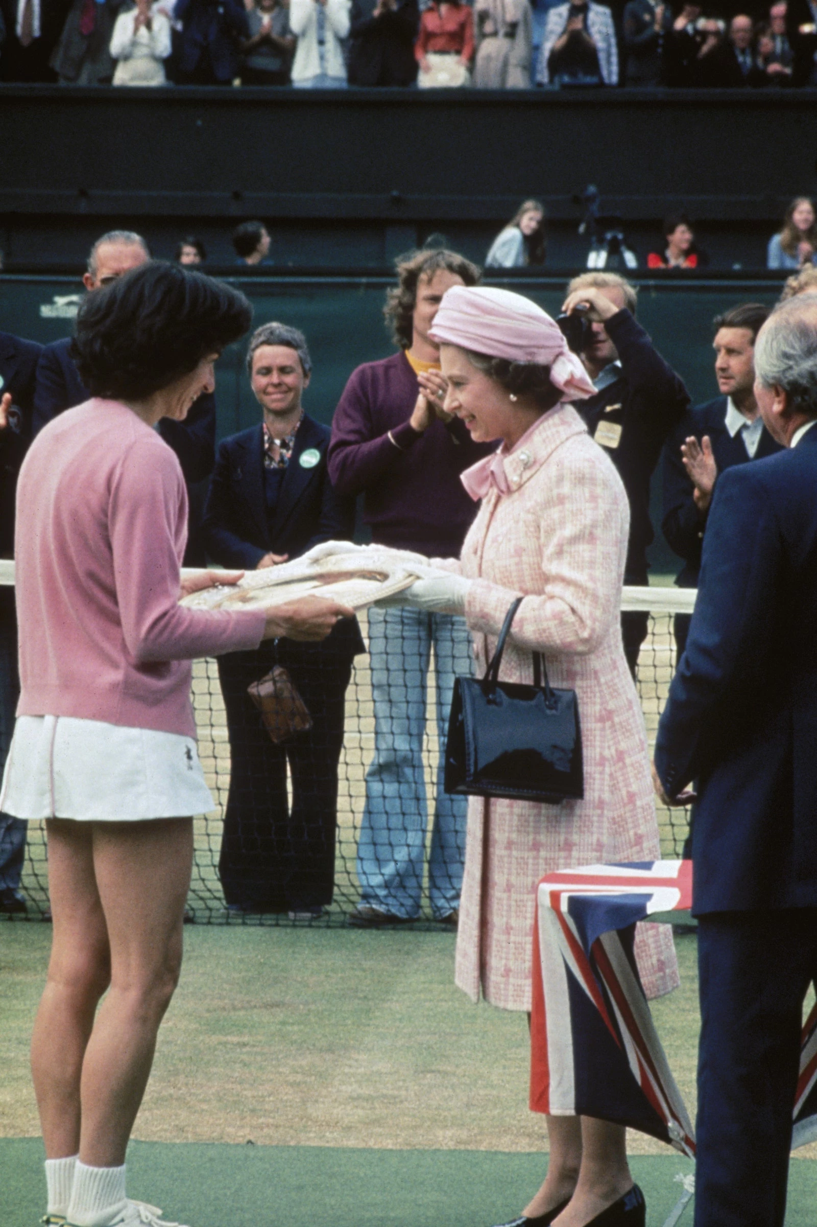 1 липня 1977 року Єлизавета II в блідо-рожевому ансамблі вручила британці Вірджинії Вейд нагороду за перемогу в жіночому одиночному розряді.