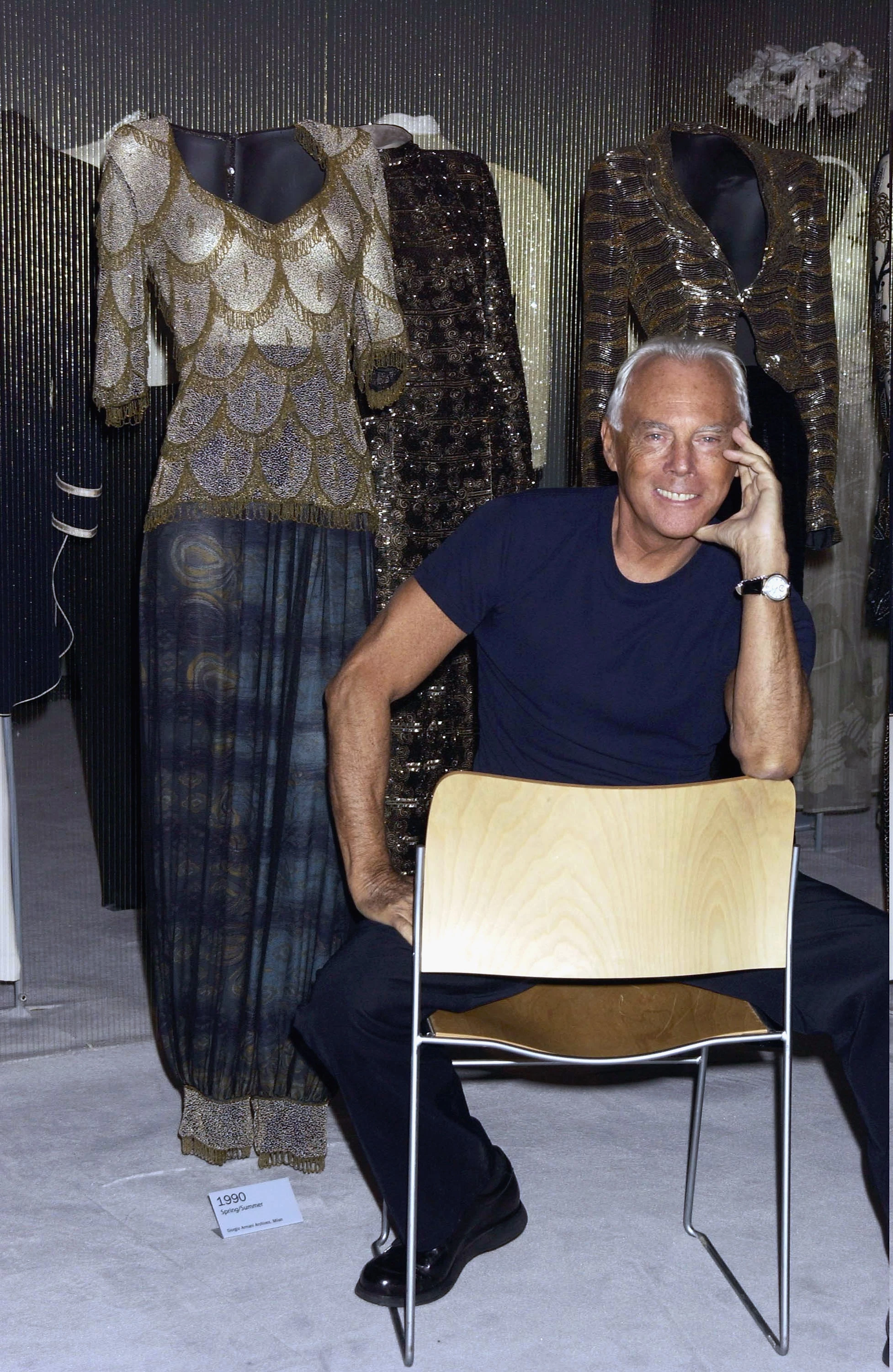 Джорджо Армані на відкритті виставки Giorgio Armani Retrospective у Королівській академії мистецтв у Лондоні, 14 жовтня 2003 року. Дизайнер позує поруч з костюмами Armani з фільму 